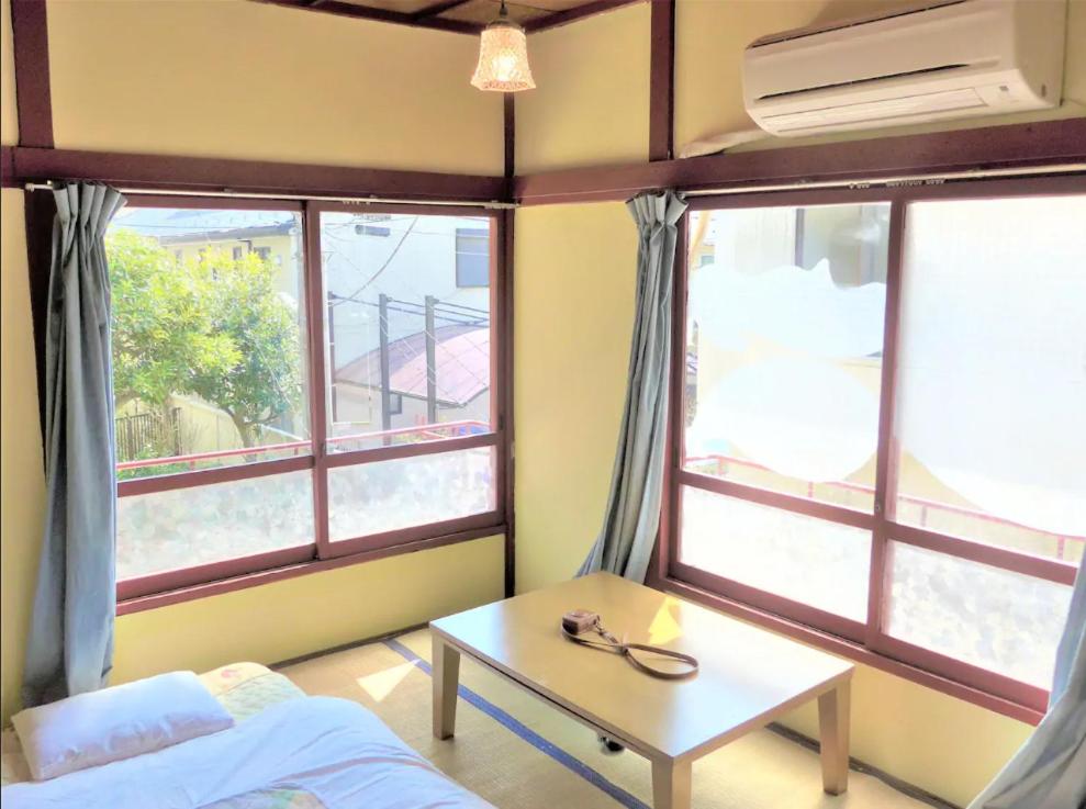 Zimmer mit 2 Fenstern, einem Tisch und einem Bett in der Unterkunft Artist's Studio in Mitaka