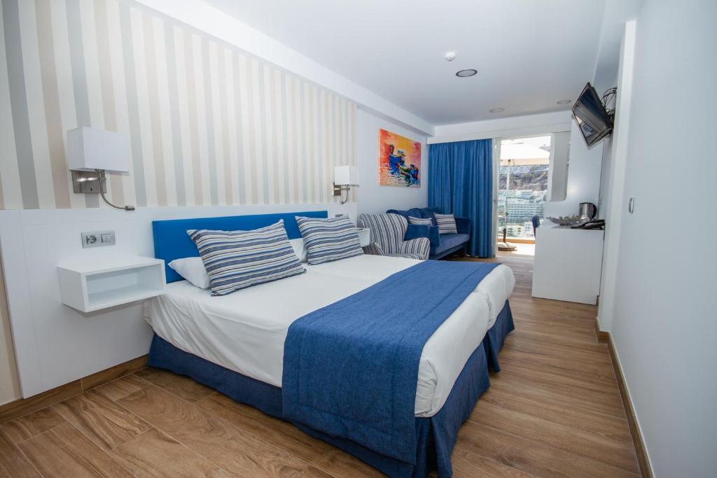 a bedroom with a blue and white bed with pillows at IG Nachosol Atlantic & Yaizasol by Servatur - Adults Only in Puerto Rico de Gran Canaria