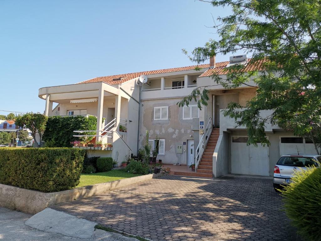 a white house with a car parked in the driveway at Apartments Dolores in Šibenik