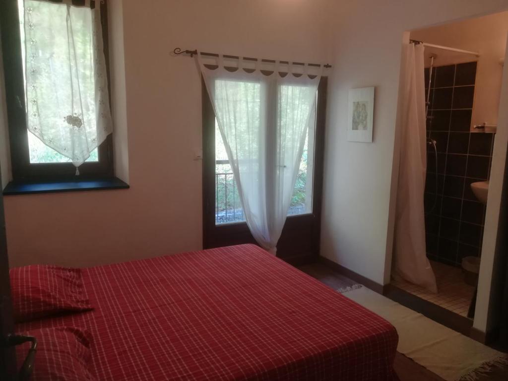 a bedroom with a red bed and a window at Gîte Belle Valette in Prads-Haute-Bléone