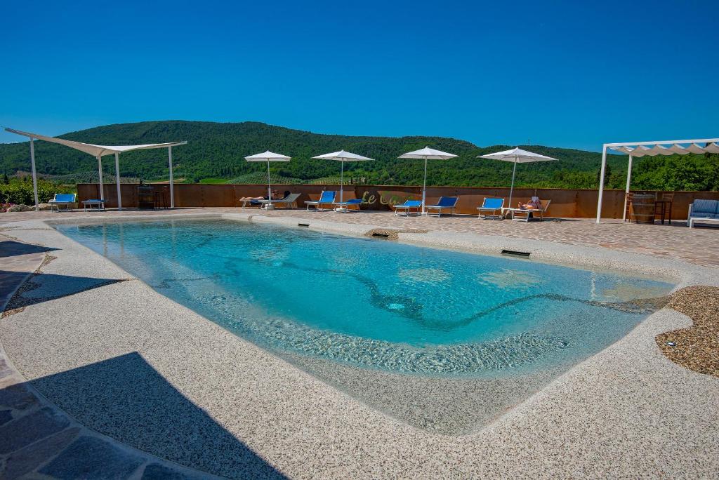 una piscina con acqua blu, sedie e ombrelloni di Casa Vacanze Le Case a San Gimignano