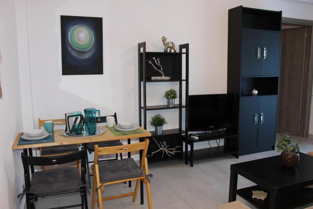 a living room with a table and chairs and a television at Stelianas Apartment in Zakynthos Town