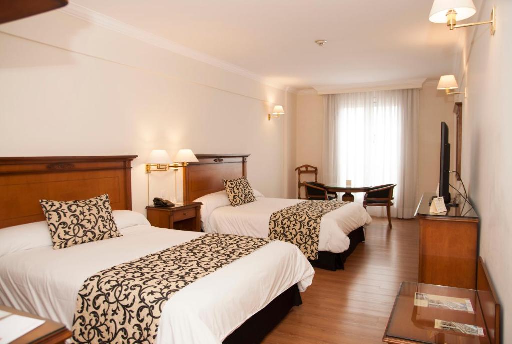 a hotel room with two beds and a television at Scala Hotel Buenos Aires in Buenos Aires