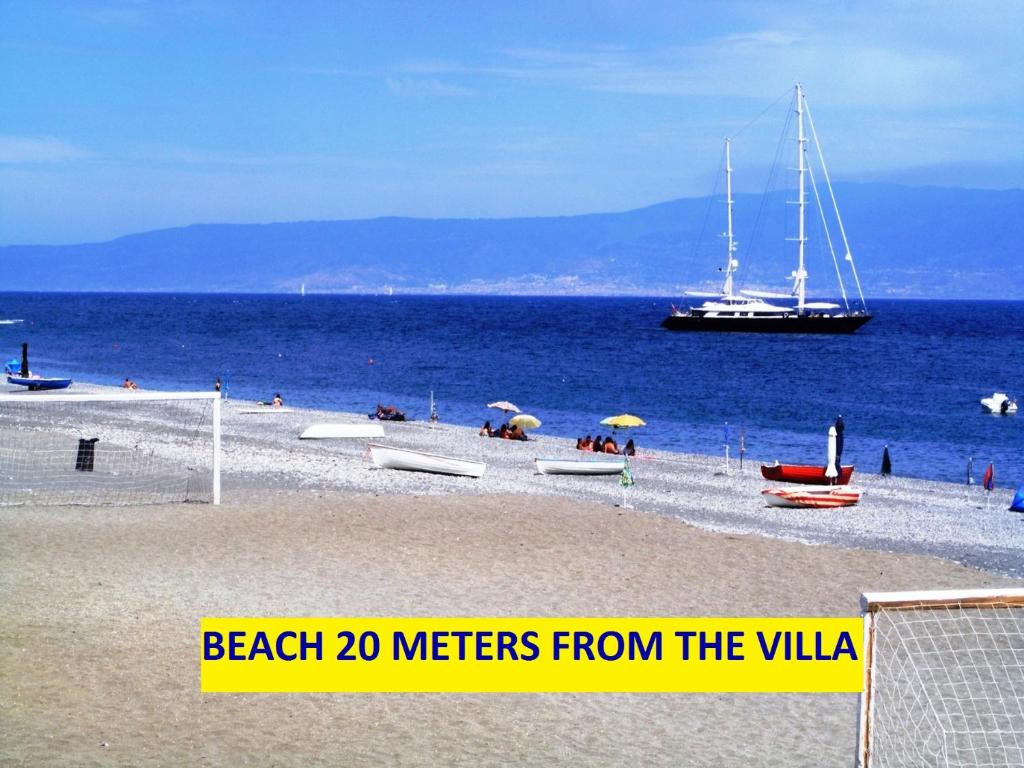 a beach meters from the villa with a boat in the water at Villetta singola "Lilla" in Alì Terme