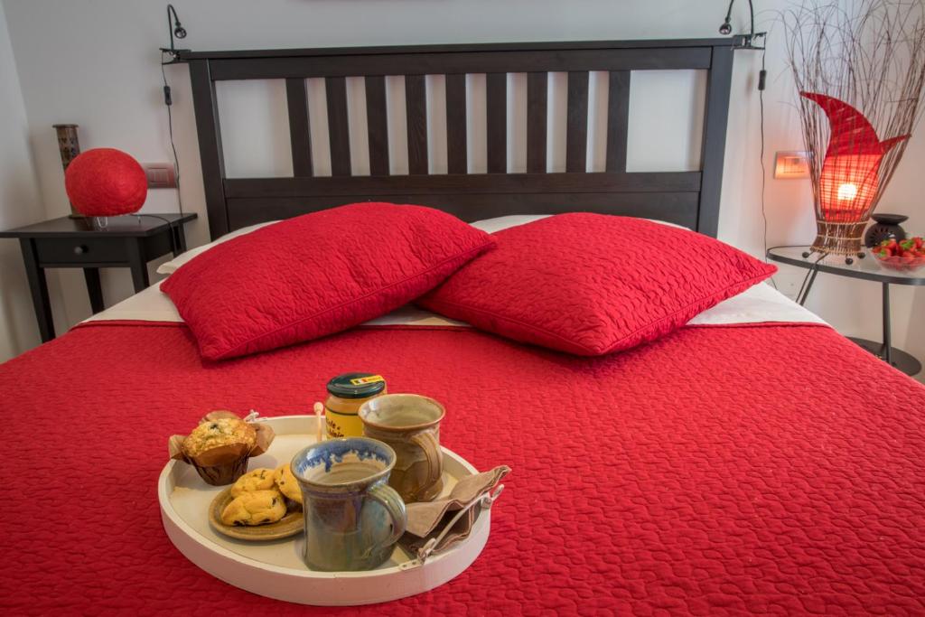 a tray of food on a bed with red pillows at Bio B&B Vivere la Vita in Polpenazze del Garda