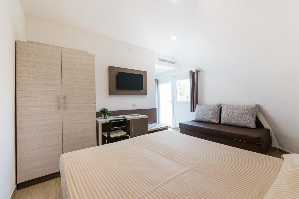 a bedroom with a bed and a couch and a television at Torre Cintola Greenblu Sea Emotions in Monopoli