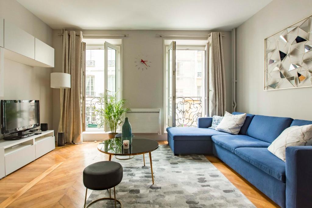 a living room with a blue couch and a table at Veeve - Jazzy Blues by Châtelet in Paris