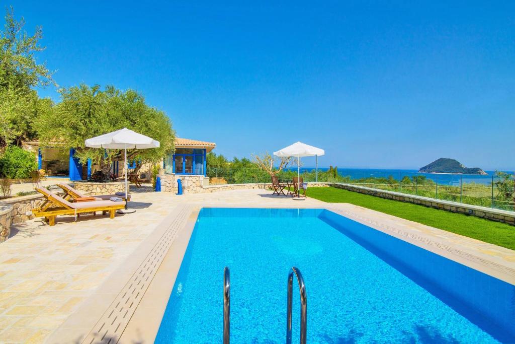 a blue swimming pool with a view of the ocean at Villa Vakis in Lithakia