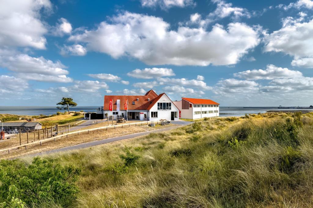a house on the beach next to the ocean at Stayokay Hostel Terschelling in West-Terschelling