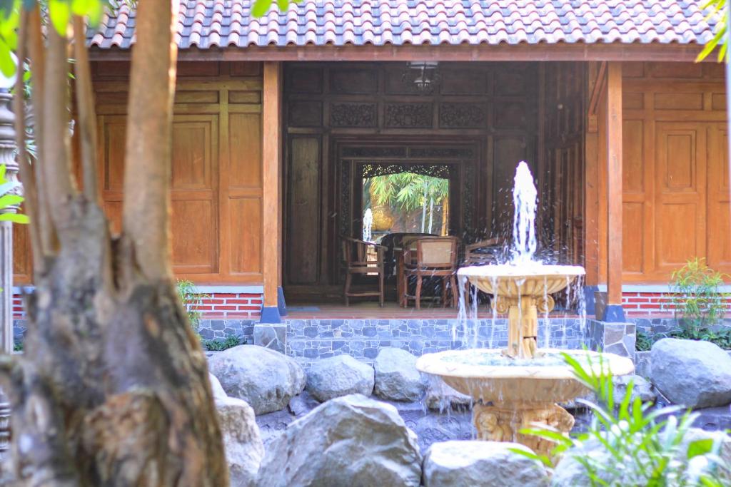 une fontaine en face d'une maison avec un bâtiment dans l'établissement Pendhapa Art Space - PAS Limasan Homestay, à Yogyakarta