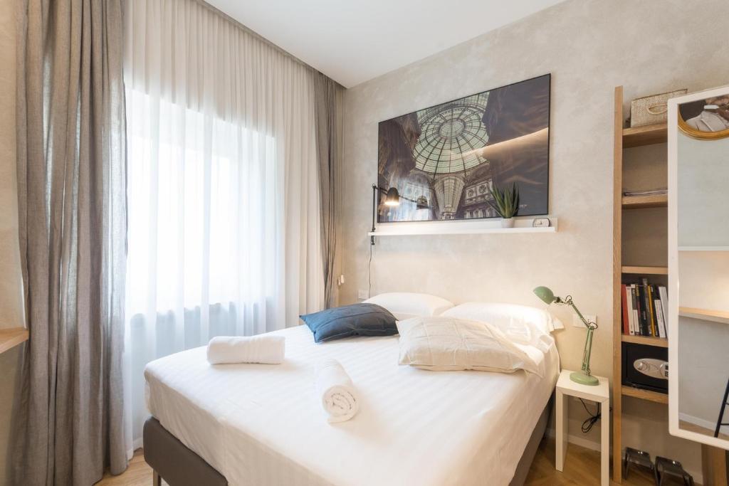um quarto com uma cama branca e uma janela em Duomo Deluxe Room em Milão