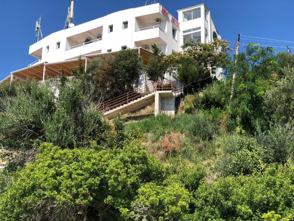 a white building on top of a hill with trees at Envi Hotel in Vlorë