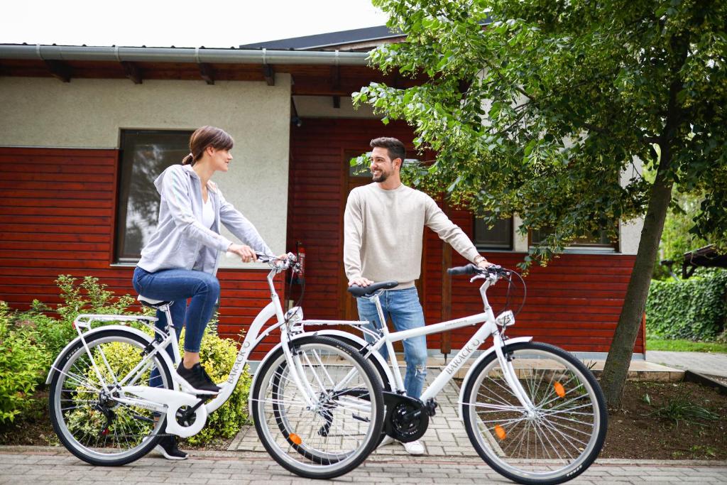 um homem e uma mulher de pé ao lado de suas bicicletas em Barack Thermal & Natura Apartments em Tiszakécske