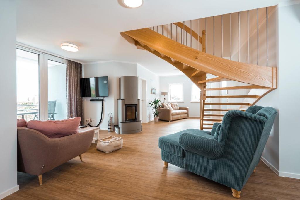 a living room with a staircase and a couch and chairs at Haus Seeweg in Elsterheide