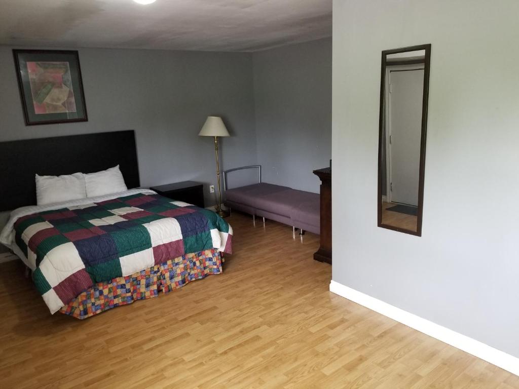 a bedroom with a bed and a table and a mirror at Eastwood Motel in Woodstock