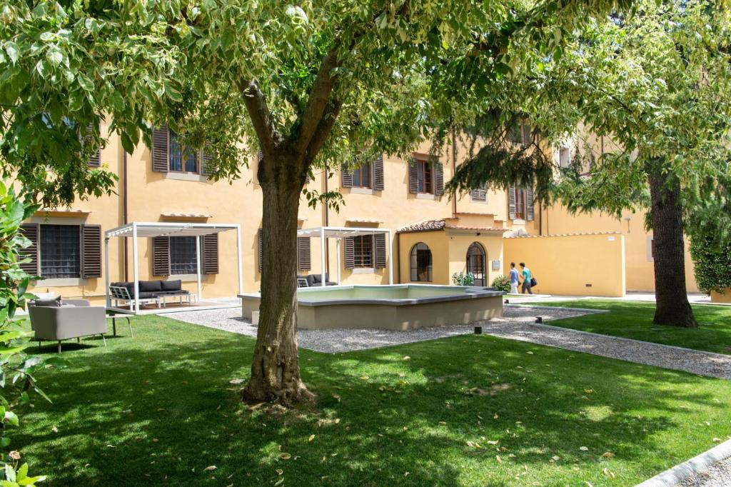 フィレンツェにあるオルト コンヴェントの木の植わる庭にプールがある建物