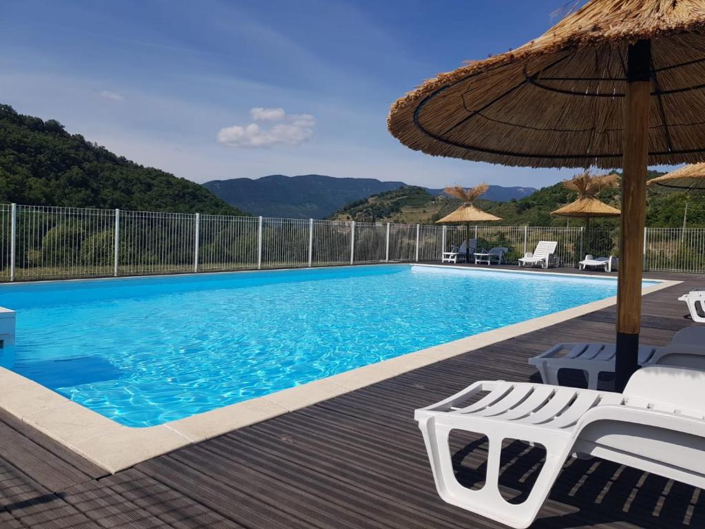 einen Pool mit Stühlen und einem Sonnenschirm in der Unterkunft Les gîtes de Moussan in Montbrun-les-Bains