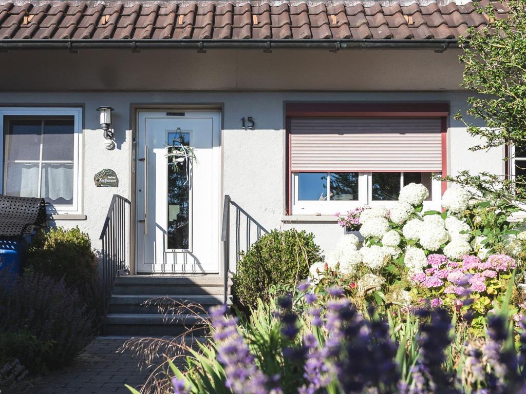 a house with a white door and flowers at Ferienwohnung im Fischerhäusle in Nonnenhorn
