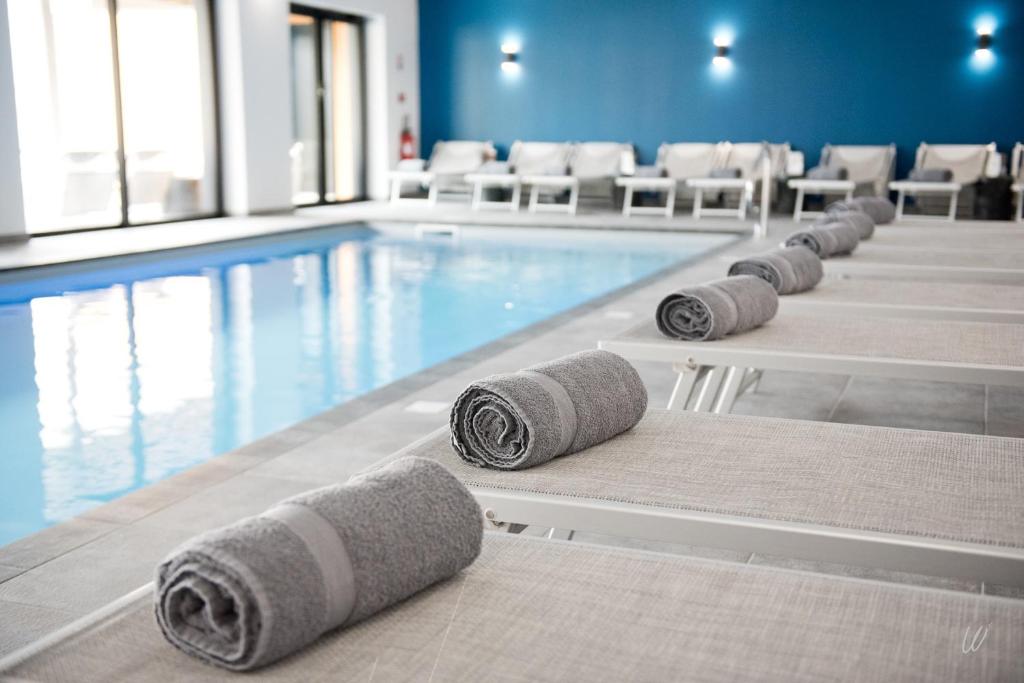una piscina con varias toallas enrolladas en los regazos en Armes de Champagne, en Châlons-en-Champagne