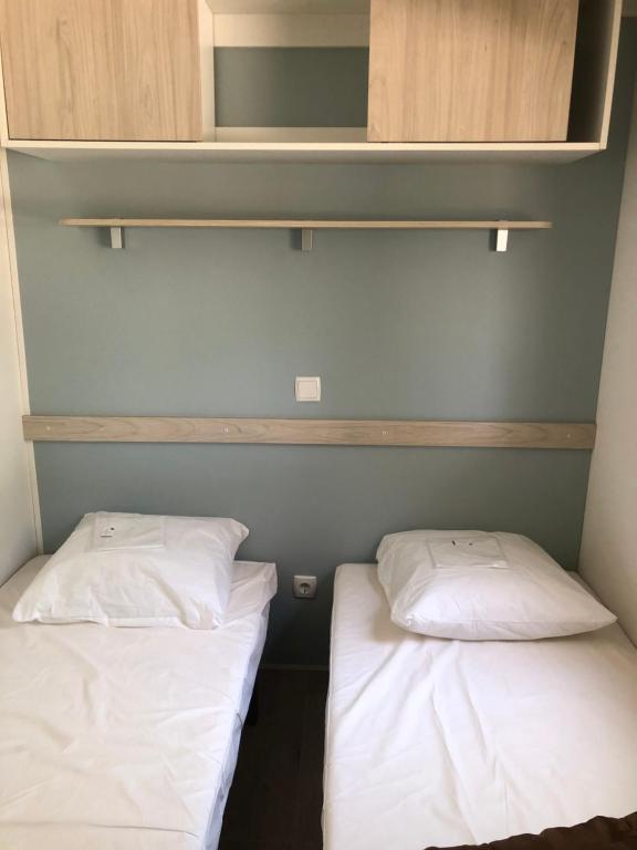 two beds in a small room with white pillows at Camping le Rhône in Tournon-sur-Rhône