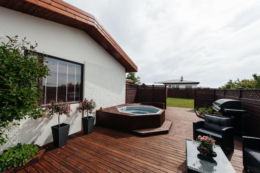 a deck with a jacuzzi tub in a backyard at Comfort and Rest in Sandgerði