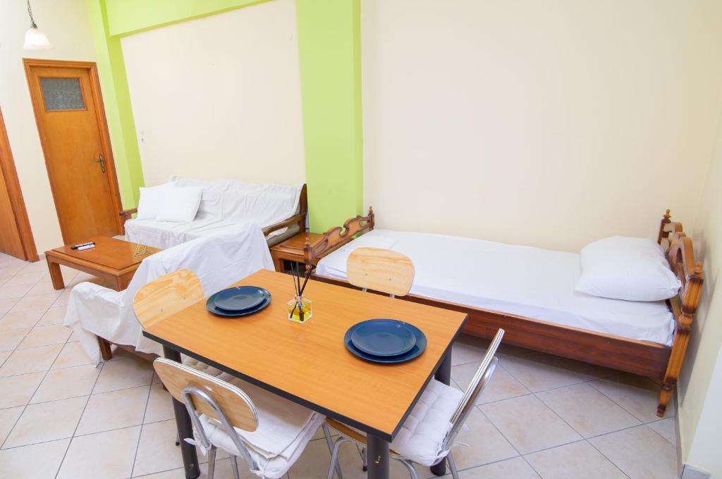 a room with two beds and a table and chairs at Peroulia apartments in Kómpoi