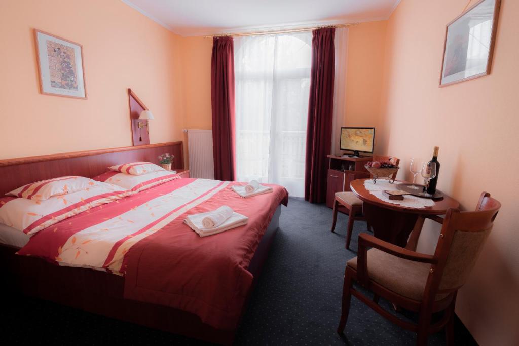 um quarto de hotel com uma cama, uma secretária e uma mesa em Boglárka Panzió - Étterem em Mezőkövesd