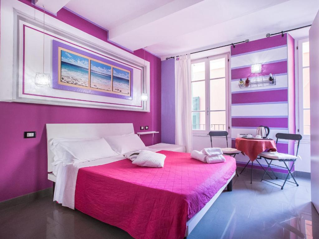 una camera da letto con pareti viola e un letto con una coperta rosa di I Coralli rooms & apartments a Monterosso al Mare