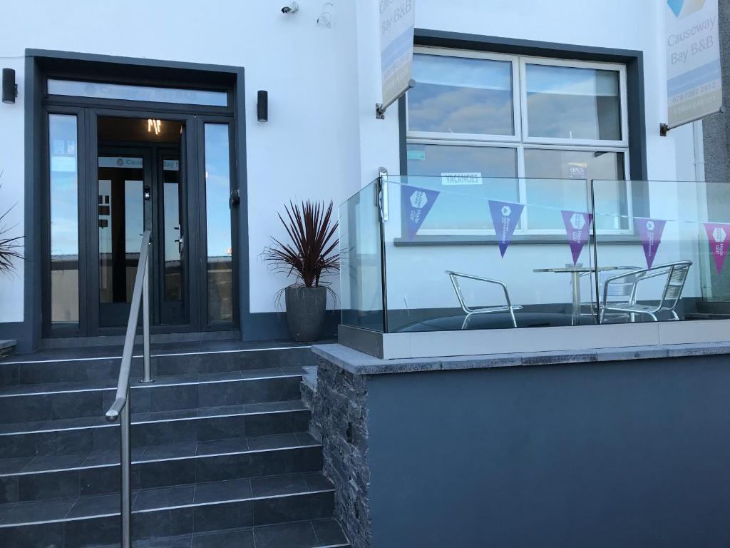 um edifício com duas cadeiras e uma mesa em frente em Causeway Bay Guesthouse Portrush em Portrush