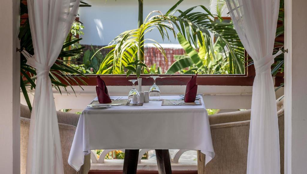 a white table with red pillows sitting in front of a window at La Rivière d' Angkor Resort in Siem Reap