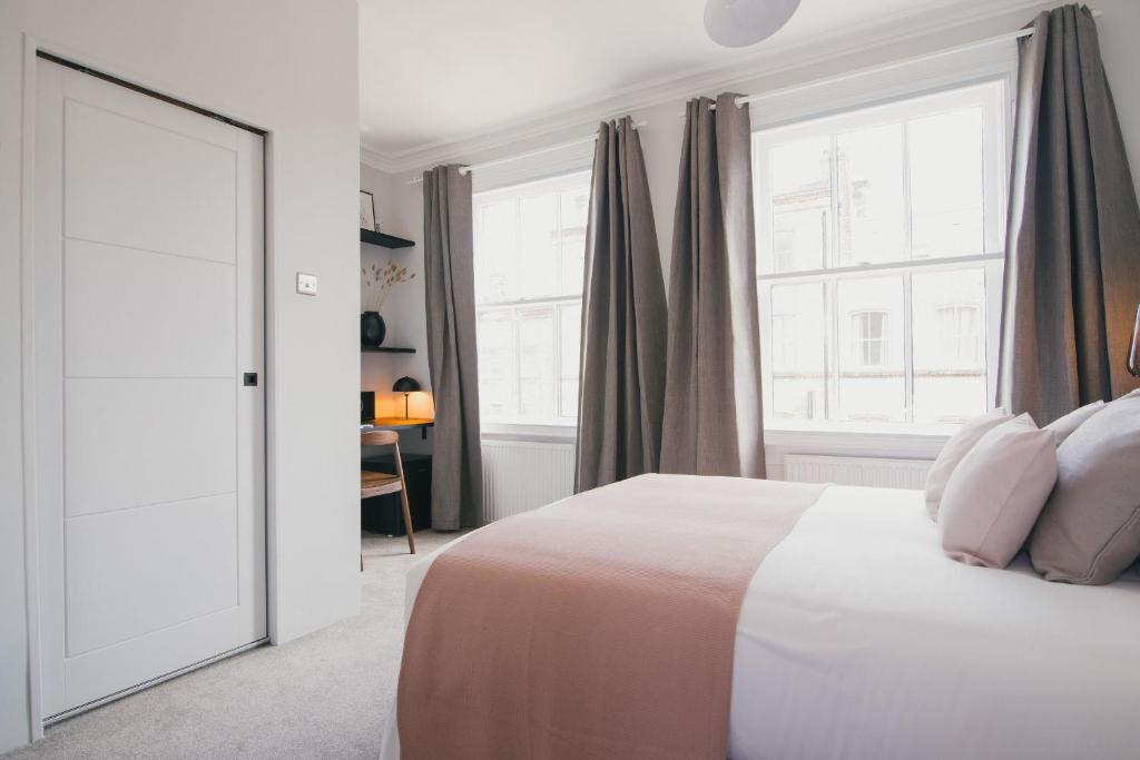 a white bedroom with a bed and a window at D8 - Shoreditch in London
