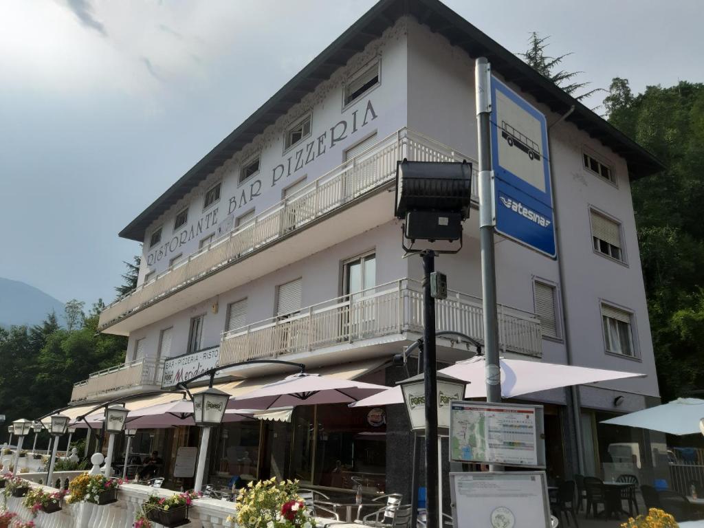 a large white building with umbrellas in front of it at Albergo Meridiana in Pergine Valsugana