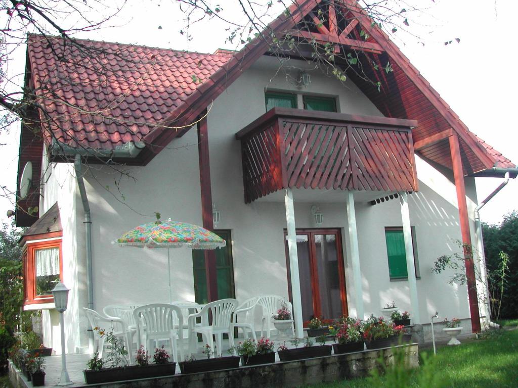 une maison blanche avec des chaises et un parasol dans l'établissement Beatrix Üdülőház, à Balatonberény