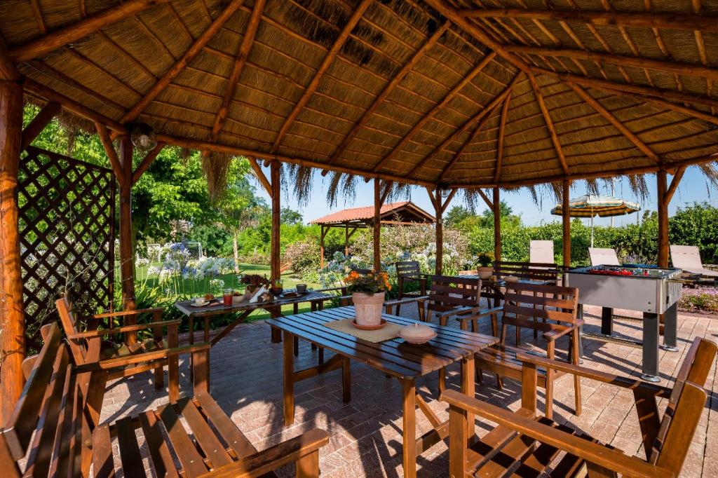 um restaurante com mesas e cadeiras de madeira e um grande guarda-sol em Oasi Caprolace em Sabaudia