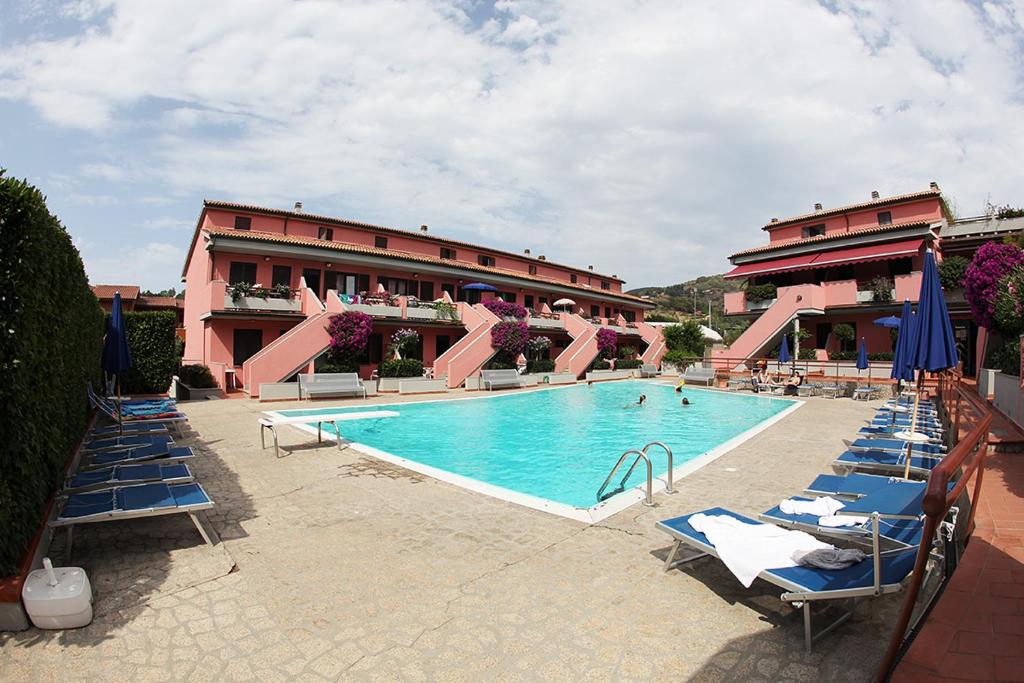 a swimming pool with lounge chairs and a hotel at Elba Vip in Porto Azzurro