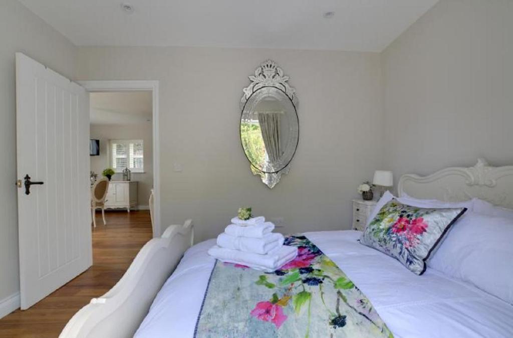 Cama blanca en habitación con espejo en The Pavilion at Brunger House, en Tenterden