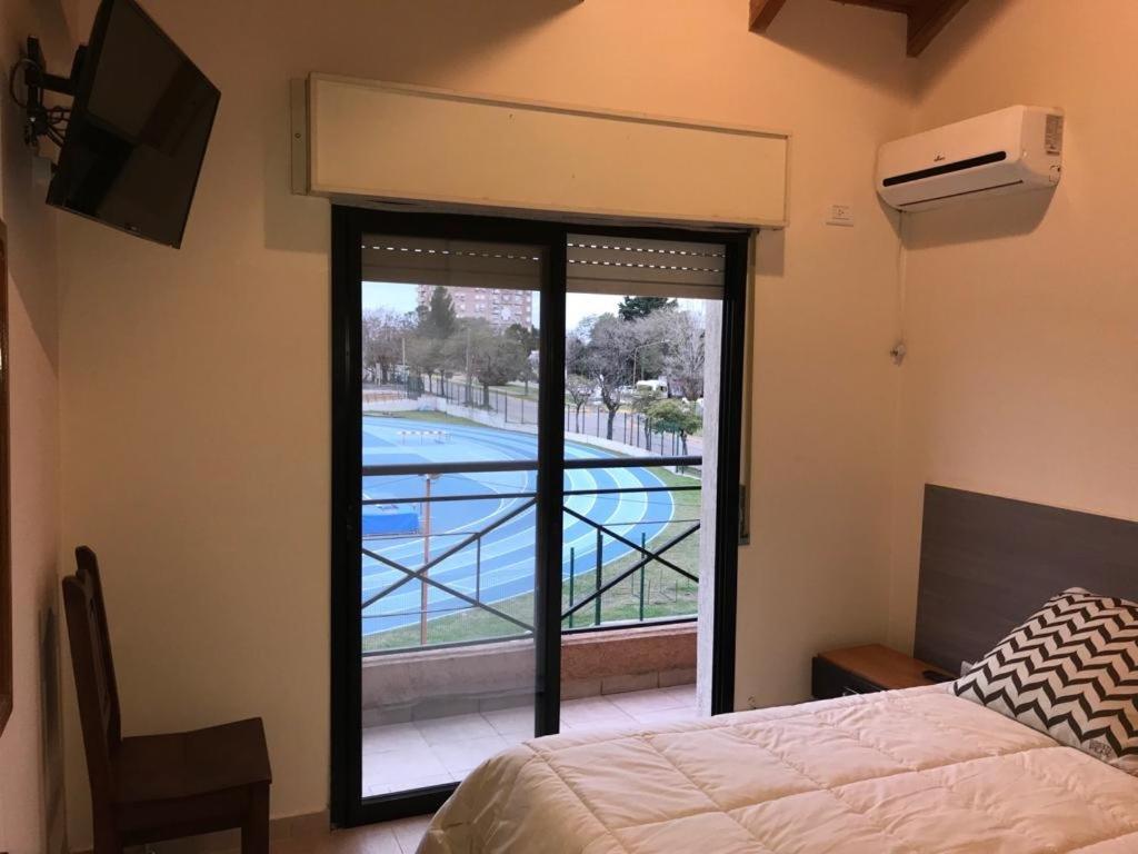 1 dormitorio con vistas a la piscina a través de una ventana en OLÍMPICO en Concepción del Uruguay