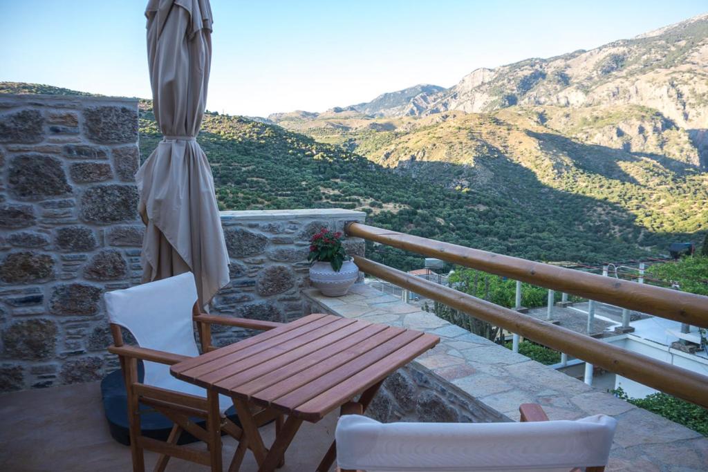 a wooden table and chairs on a balcony with mountains at To Spiti mas in Sougia