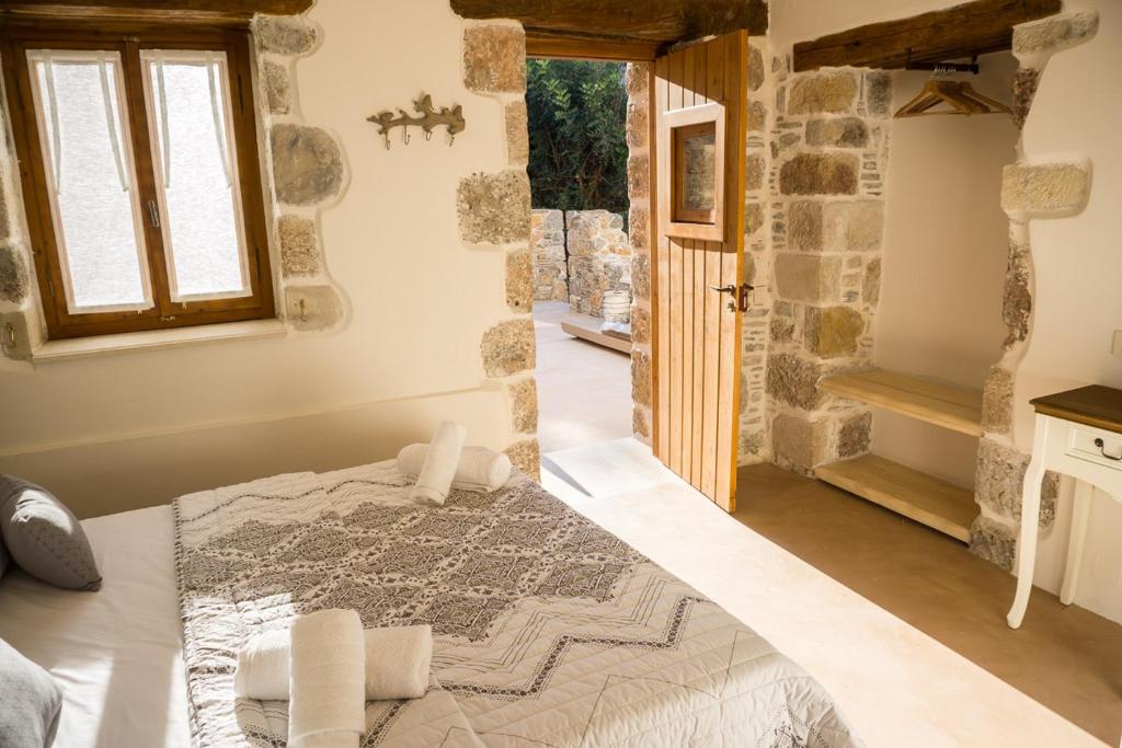a bedroom with a large bed and a stone wall at To Spiti mas in Sougia