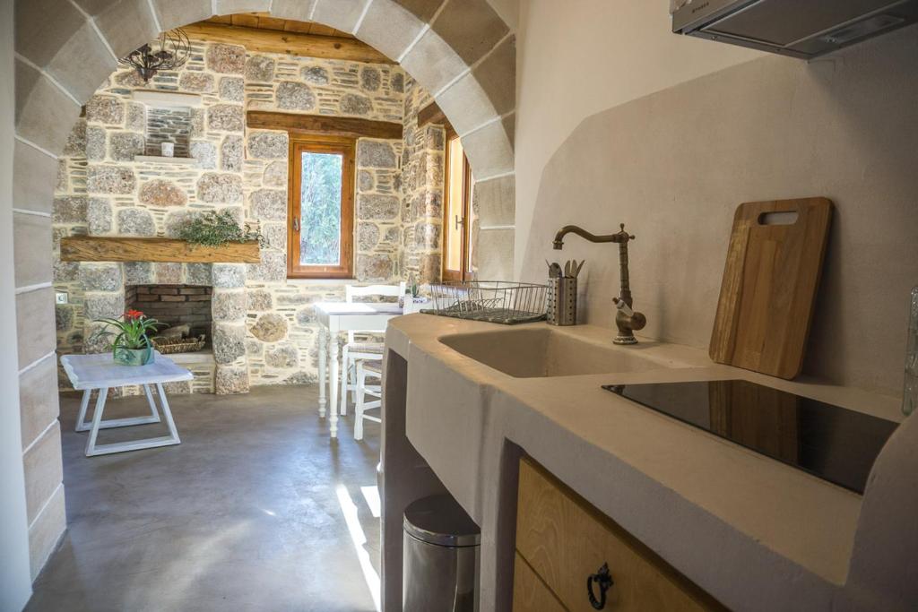 a kitchen with a sink and a stone wall at To Spiti mas in Sougia