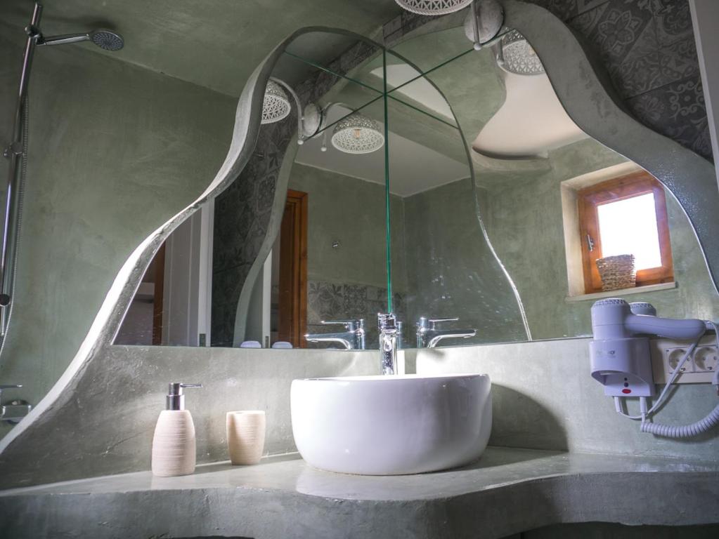 a bathroom with a sink and a large mirror at To Spiti mas in Sougia