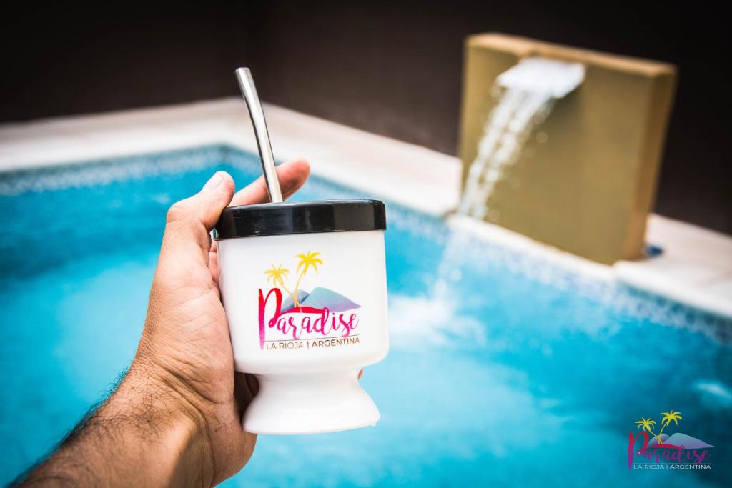 a person holding a coffee cup in front of a pool at Complejo Paradise in La Rioja