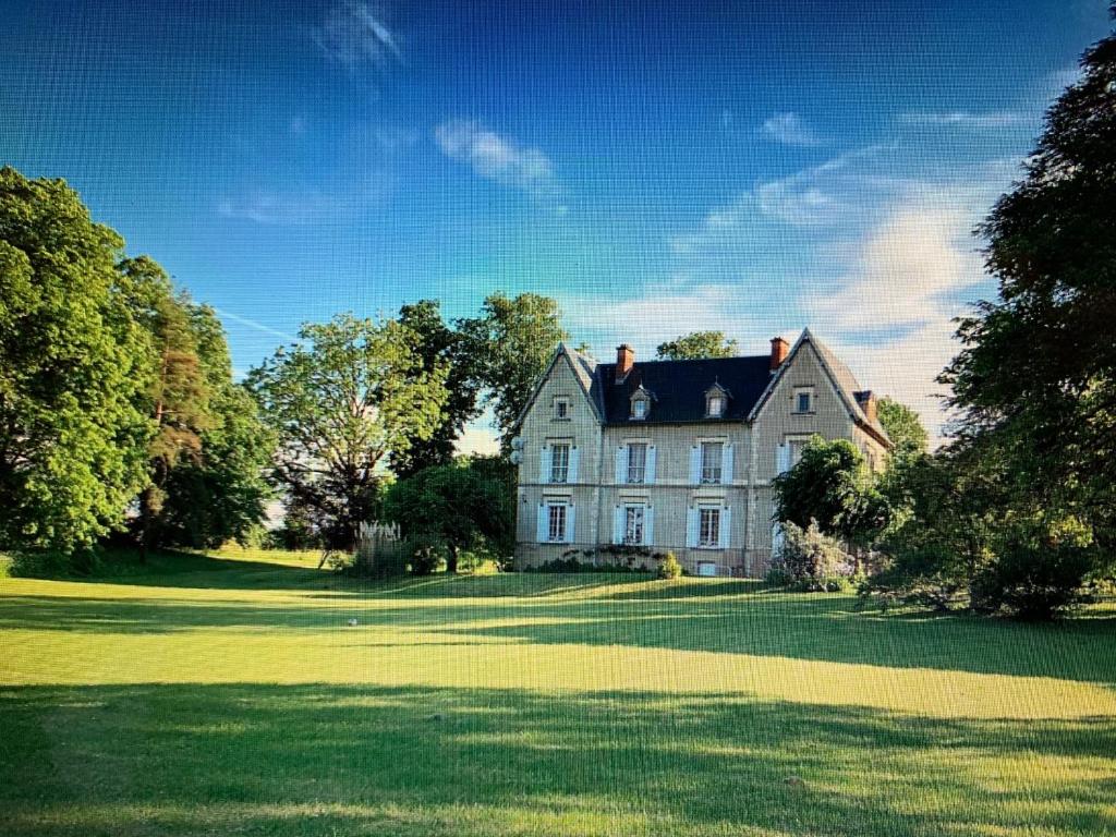 une grande maison blanche sur une pelouse verdoyante dans l'établissement Le Donjon d'Anthon, à Anthon