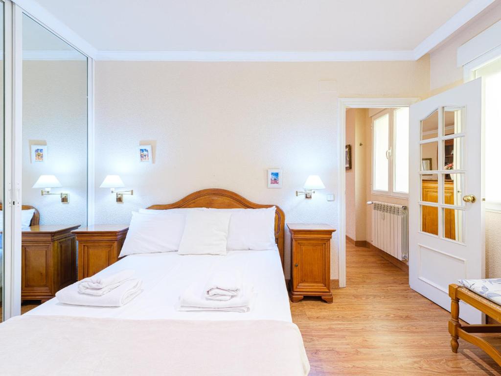 1 dormitorio con 1 cama con sábanas blancas y espejo en My City Home- Cosy apartament in Chamberi, en Madrid