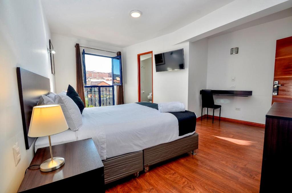 Schlafzimmer mit einem Bett, einem Schreibtisch und einem Fenster in der Unterkunft Ankawa Hotel Boutique in Cusco