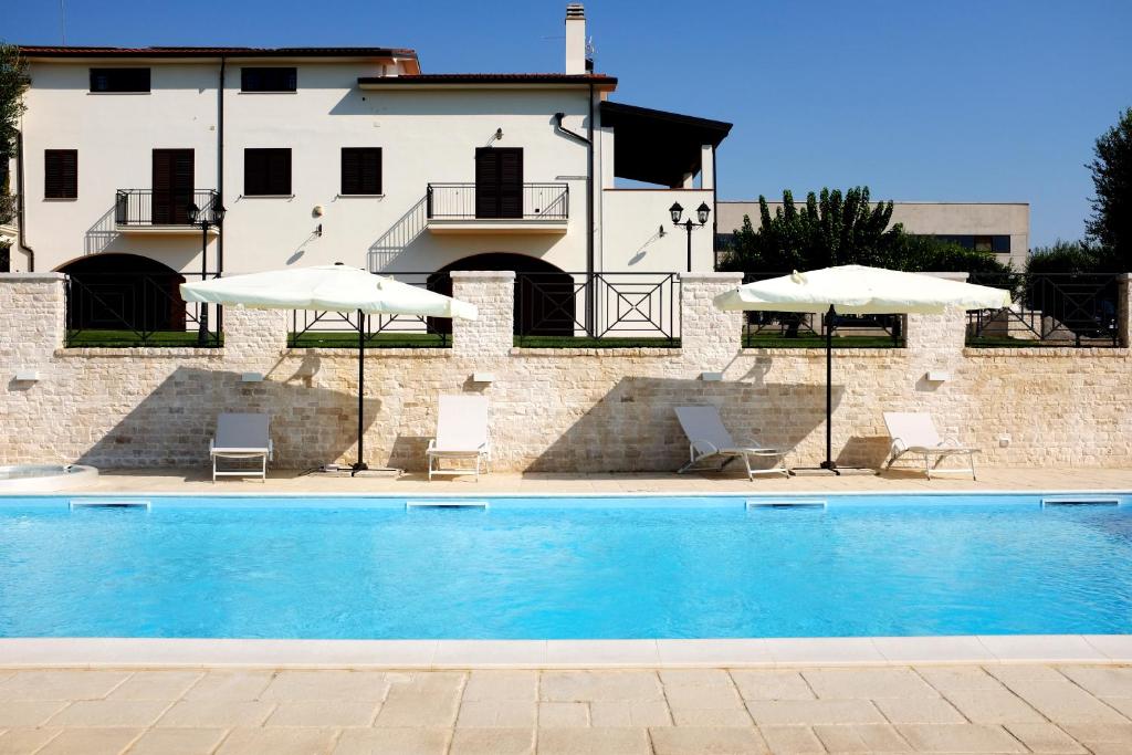 una piscina con sillas y sombrillas frente a un edificio en Villa Torre Cantore, en Rotondella
