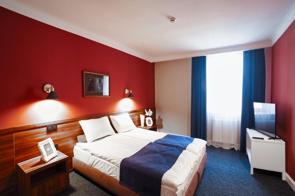 Habitación de hotel con cama y pared roja en Sherlock Holmes Boutique Hotel, en Leópolis