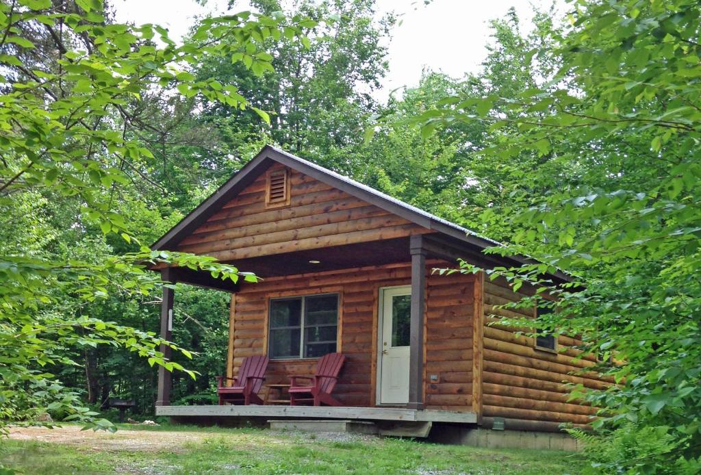 uma cabana de madeira com cadeiras no alpendre em Sterling Ridge Resort em Jeffersonville