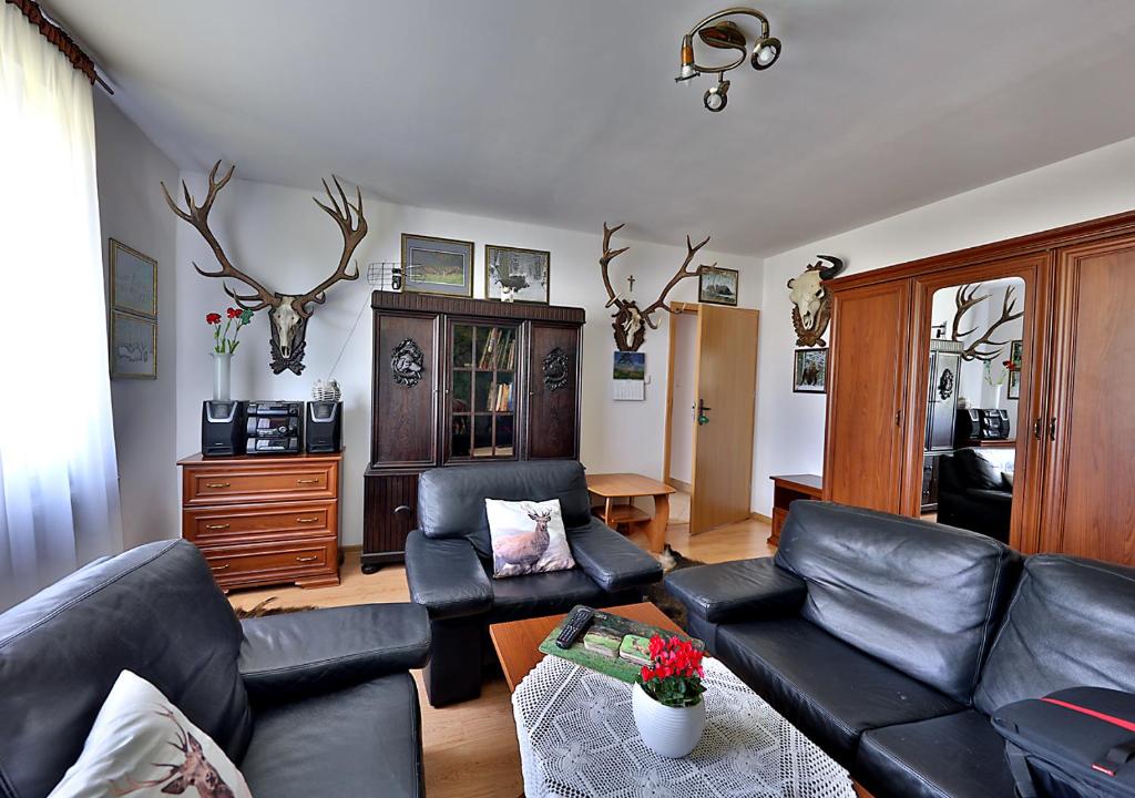 a living room with black leather furniture and antlers on the wall at Apartamenty w Puszczy Boreckiej in Kruklanki