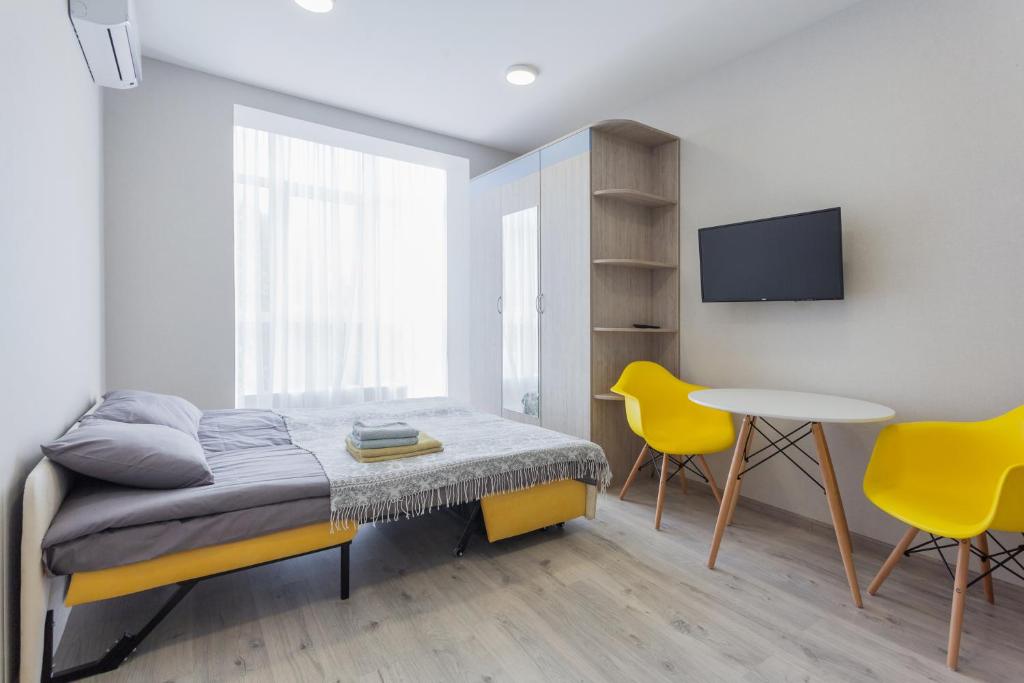 a bedroom with a bed and a table and two yellow chairs at Акварель in Kyiv